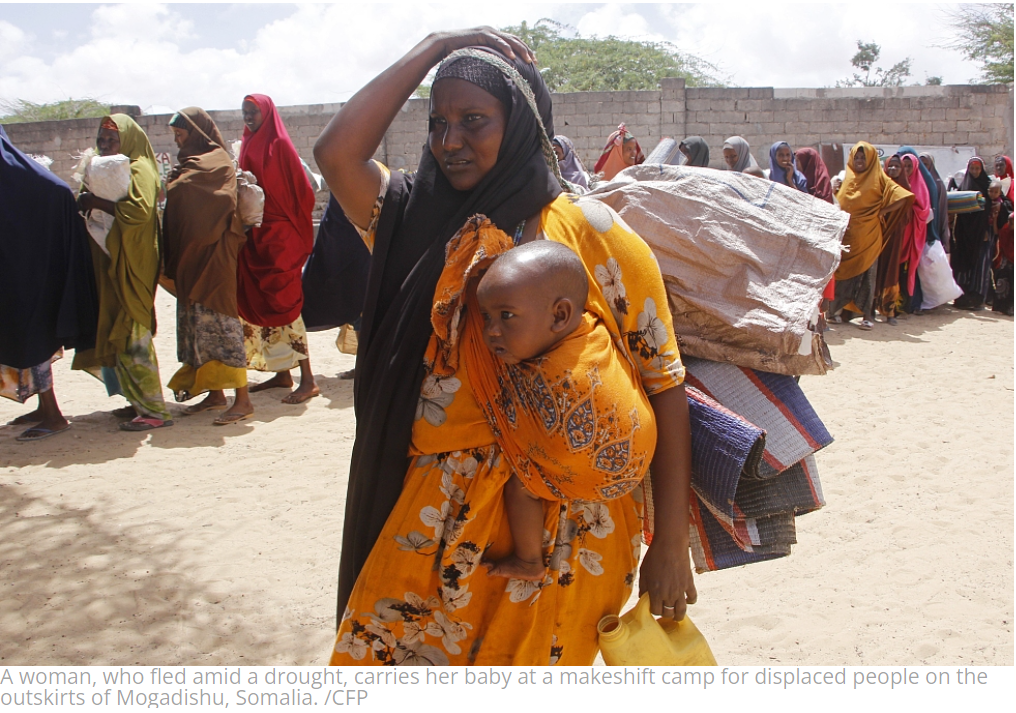 A woman, who fled amid a drought, carries her baby at a makeshift camp for displaced people on the outskirts of Mogadishu, Somalia. /CFP